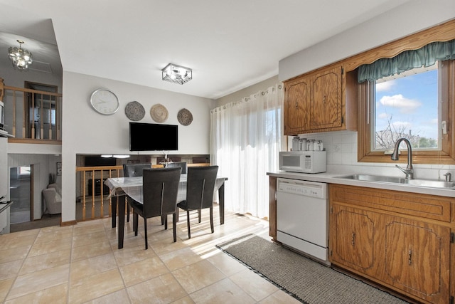 kitchen featuring a chandelier, white appliances, tasteful backsplash, and sink