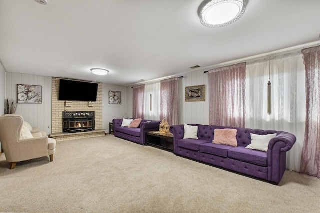 carpeted living room with a brick fireplace and wood walls