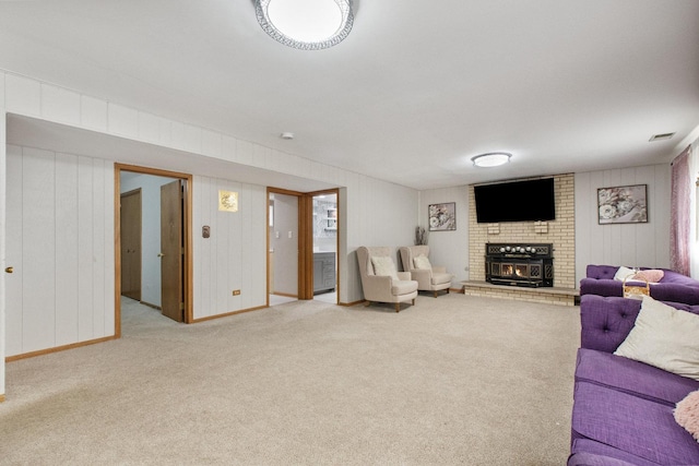 living room featuring wooden walls, light colored carpet, and a brick fireplace