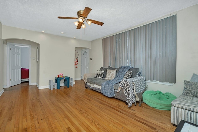 unfurnished living room featuring hardwood / wood-style flooring, ceiling fan, and a textured ceiling