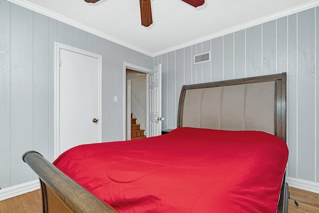 bedroom featuring hardwood / wood-style flooring, ceiling fan, and crown molding