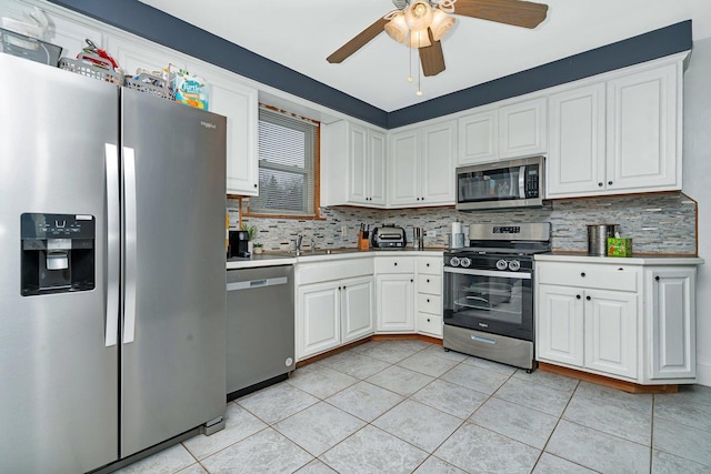 kitchen with decorative backsplash, appliances with stainless steel finishes, white cabinets, and light tile patterned flooring