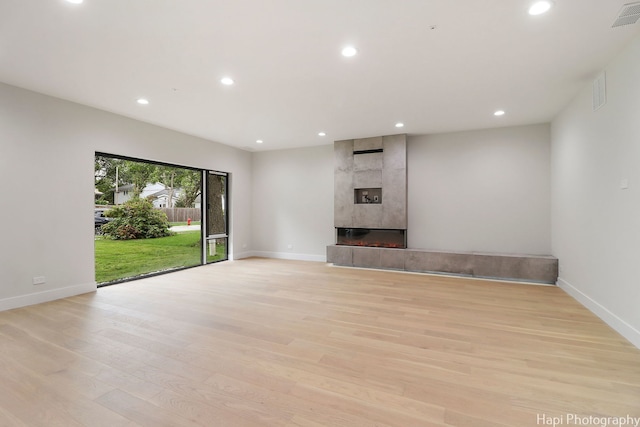 unfurnished living room with a tile fireplace and light hardwood / wood-style flooring