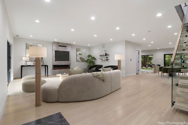 living room with a tile fireplace and light hardwood / wood-style floors