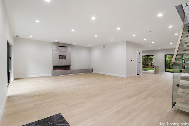 unfurnished living room with light wood-type flooring and a tile fireplace