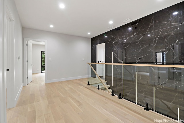 corridor with light hardwood / wood-style floors and tile walls