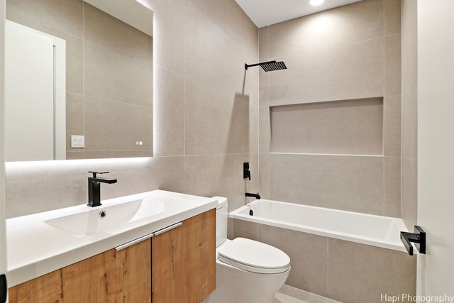 full bathroom featuring tiled shower / bath combo, toilet, tile walls, and vanity