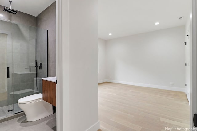 bathroom featuring vanity, hardwood / wood-style flooring, toilet, and a shower with shower door