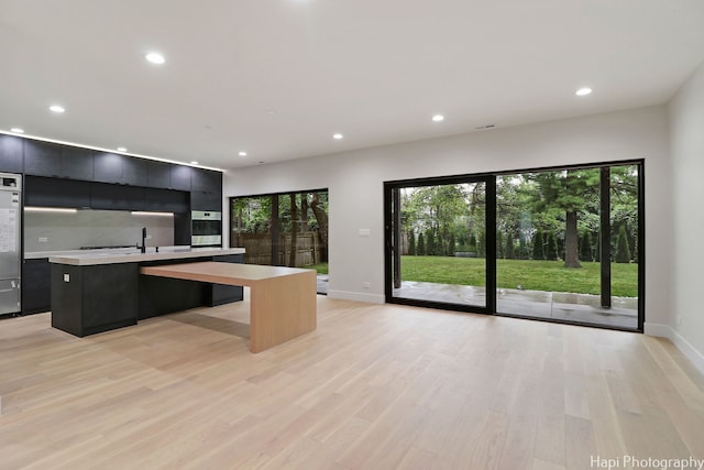 kitchen with sink, an island with sink, and light hardwood / wood-style floors