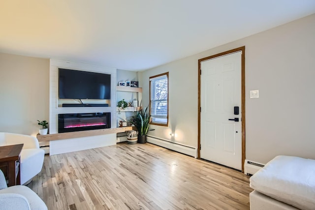 living room featuring a large fireplace, light hardwood / wood-style floors, and a baseboard heating unit