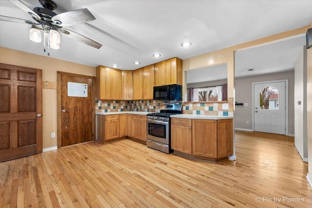 kitchen with gas stove, light hardwood / wood-style floors, ceiling fan, and backsplash