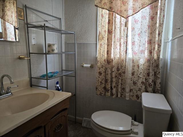 bathroom featuring tile walls, vanity, and toilet