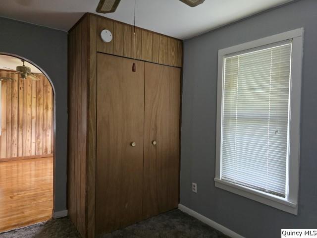 unfurnished bedroom with dark colored carpet, ceiling fan, and a closet