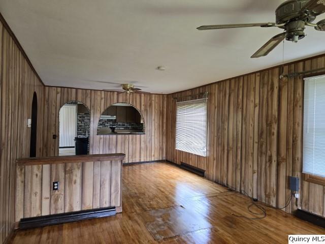 interior space featuring ceiling fan, wood-type flooring, and wood walls