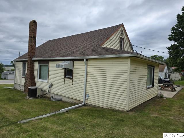 view of side of home with cooling unit and a yard