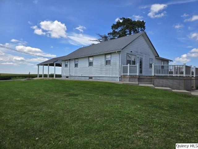 view of side of property featuring a wooden deck and a lawn