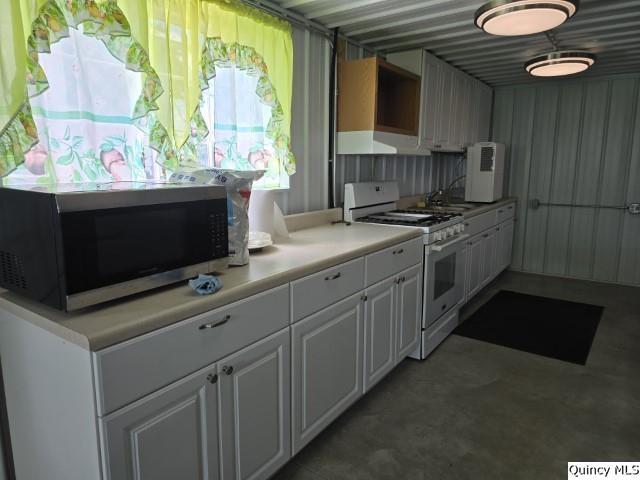 kitchen featuring white cabinetry and white gas range oven