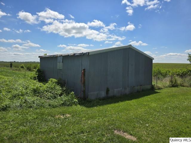 view of outbuilding with a rural view and a lawn