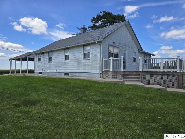 view of side of property with a wooden deck and a lawn