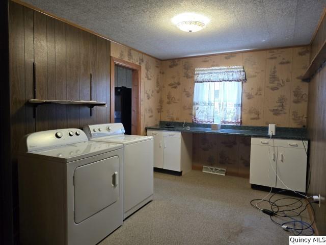 laundry room with cabinets, light carpet, a textured ceiling, and independent washer and dryer