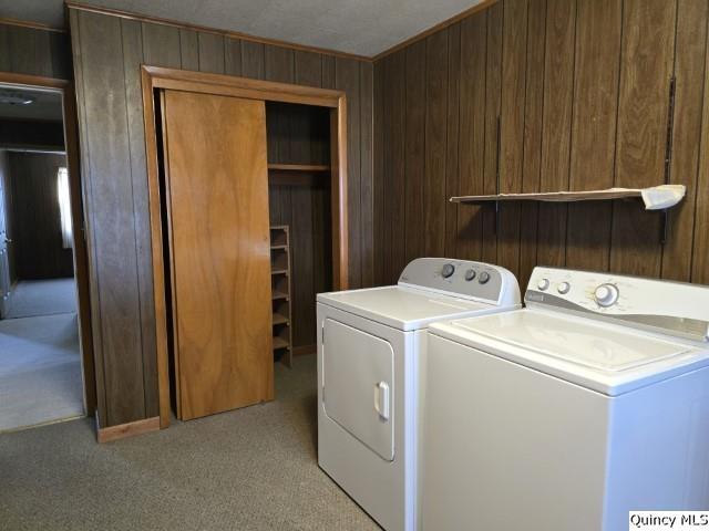 laundry room featuring washing machine and clothes dryer, wooden walls, and light carpet