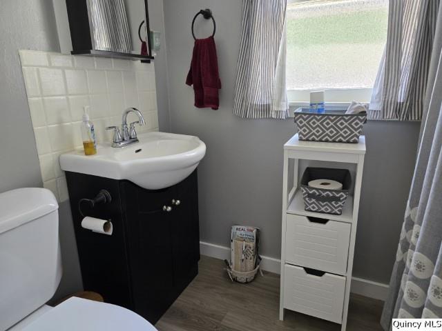 bathroom featuring decorative backsplash, wood-type flooring, vanity, and toilet