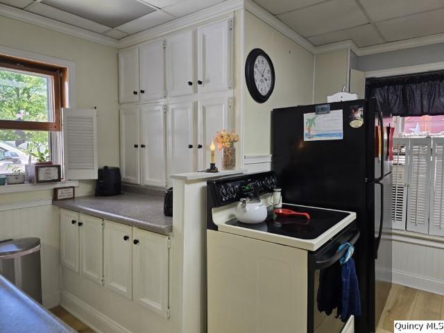 kitchen with white cabinetry, light hardwood / wood-style flooring, electric range oven, ornamental molding, and a drop ceiling