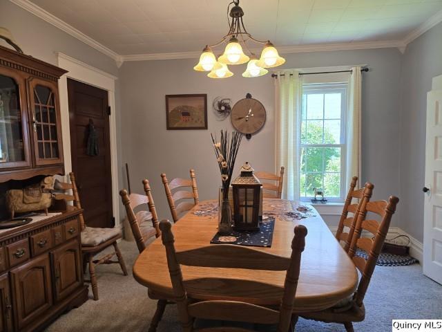 carpeted dining space with a notable chandelier and crown molding