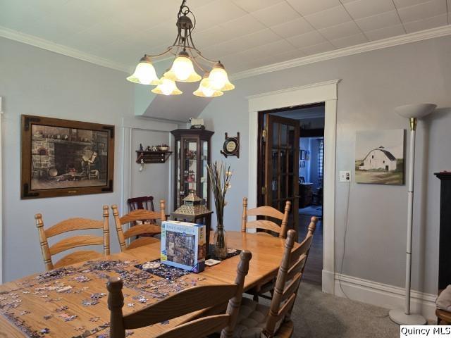 carpeted dining space featuring an inviting chandelier and ornamental molding