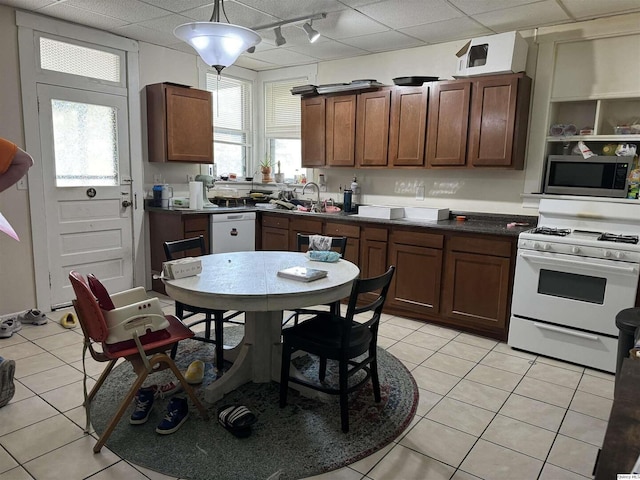 kitchen featuring light tile patterned flooring, white appliances, a healthy amount of sunlight, and a drop ceiling