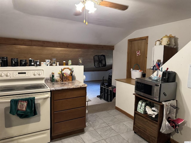 kitchen featuring lofted ceiling, light tile patterned floors, ceiling fan, wooden walls, and white range with electric stovetop