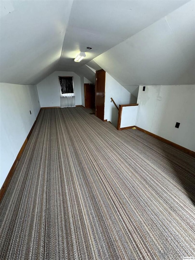 additional living space featuring vaulted ceiling and dark carpet