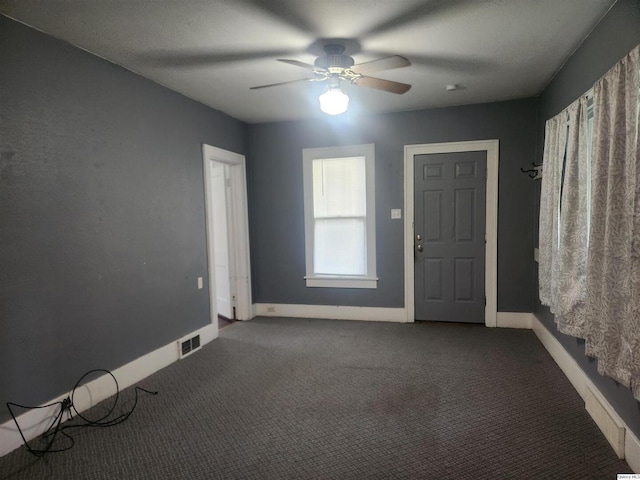 unfurnished room with dark colored carpet and ceiling fan