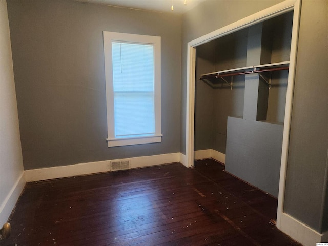 unfurnished bedroom featuring dark wood-type flooring and a closet