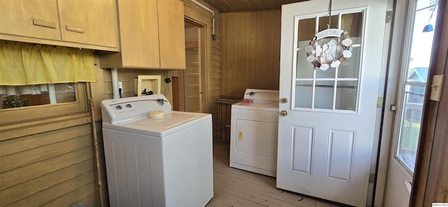 laundry area with wood walls, separate washer and dryer, cabinets, a notable chandelier, and light hardwood / wood-style floors