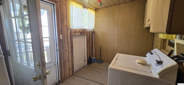 washroom featuring washer / dryer, wooden walls, light hardwood / wood-style floors, and cabinets