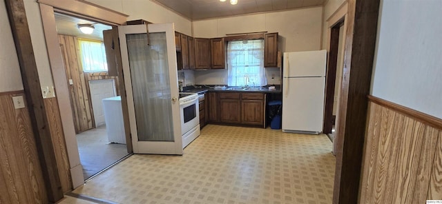 kitchen featuring sink, white appliances, and wood walls