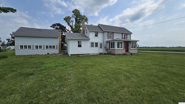 rear view of house featuring a garage and a yard