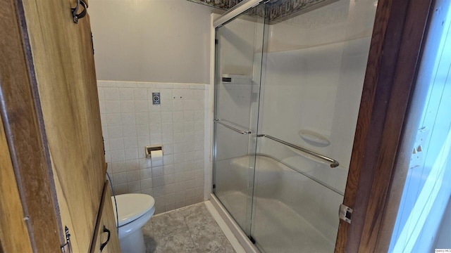 bathroom with tile walls, a shower with shower door, tile patterned floors, and toilet