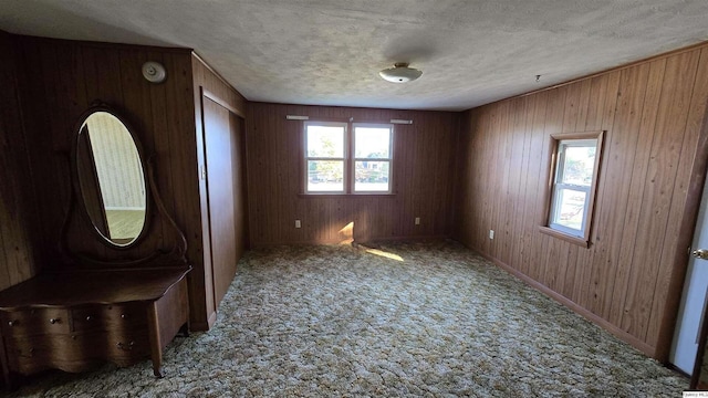 entryway featuring wooden walls, light carpet, and a textured ceiling