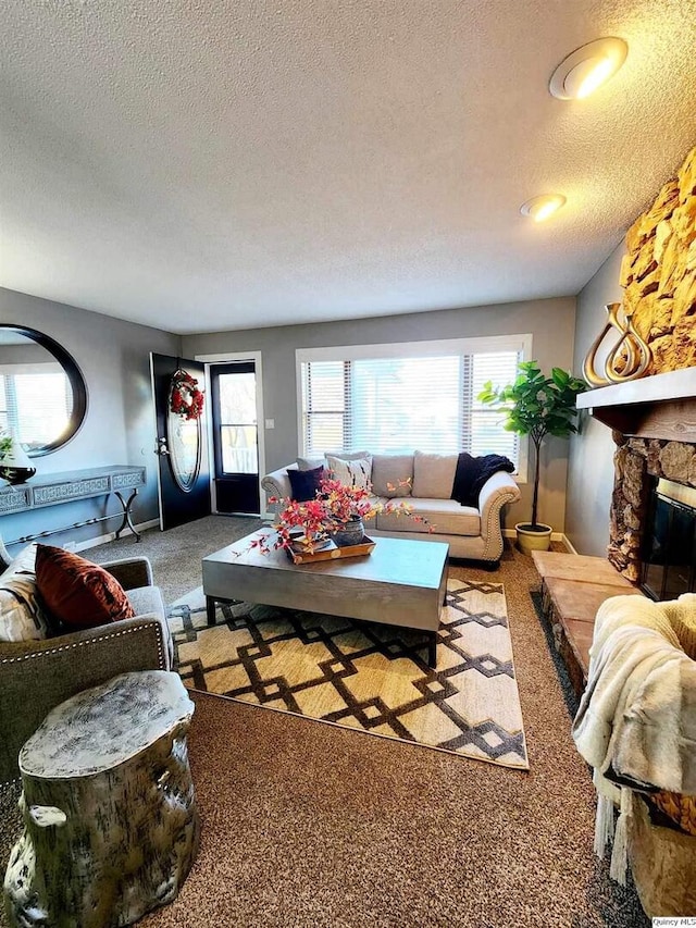 carpeted living room with a stone fireplace and a textured ceiling