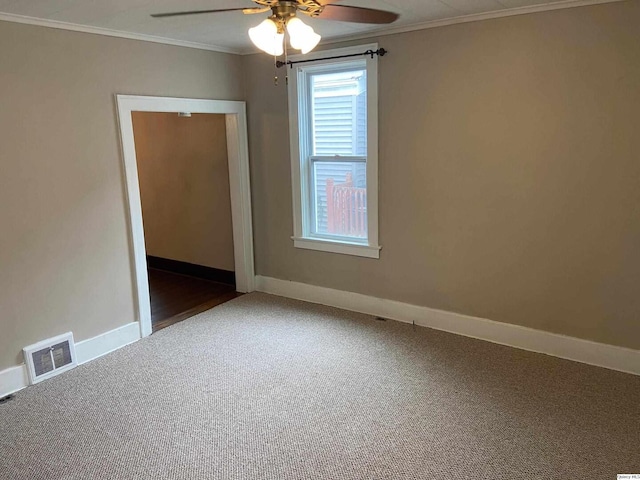 empty room with ornamental molding, ceiling fan, and dark colored carpet