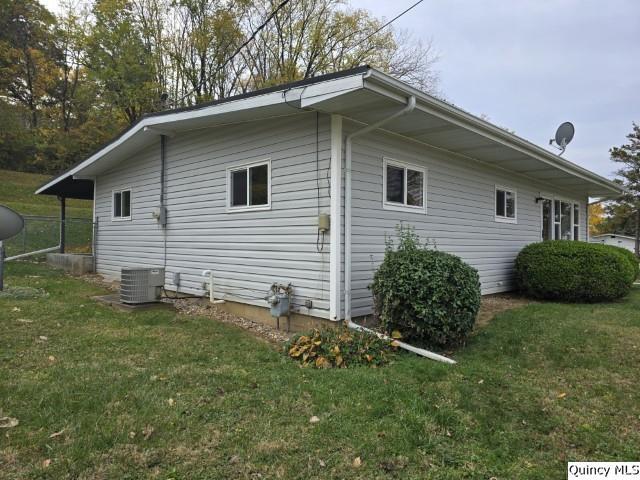 view of side of home with a yard and central AC