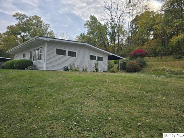 view of side of property with a carport and a lawn