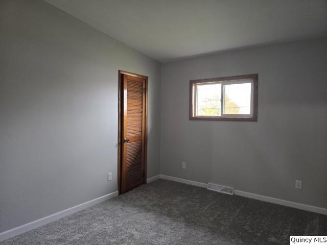 spare room featuring lofted ceiling and dark colored carpet