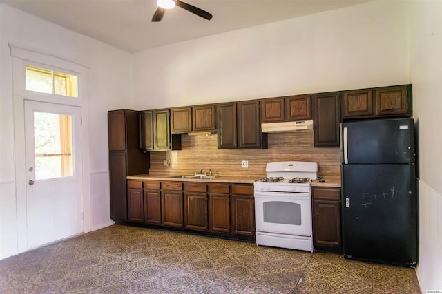 kitchen with sink, tasteful backsplash, black refrigerator, ceiling fan, and white gas range oven