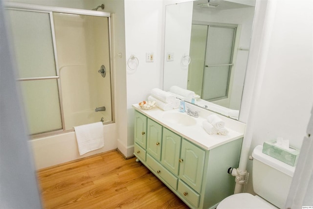 full bathroom featuring hardwood / wood-style flooring, enclosed tub / shower combo, vanity, and toilet