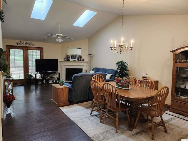 dining area featuring ceiling fan with notable chandelier, dark wood-type flooring, and lofted ceiling with skylight