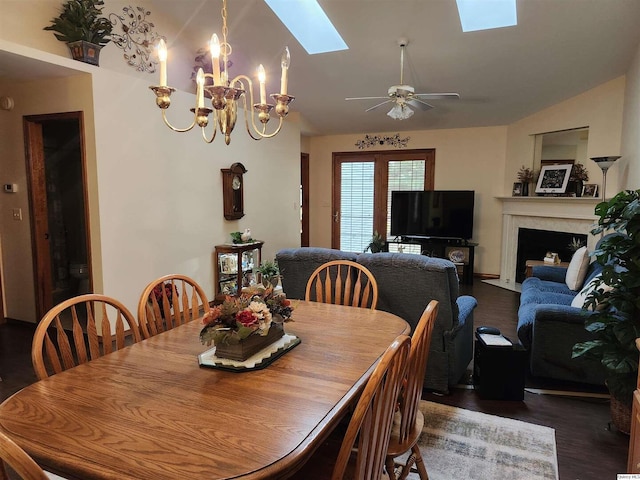 dining room with ceiling fan with notable chandelier, dark wood-type flooring, and lofted ceiling with skylight