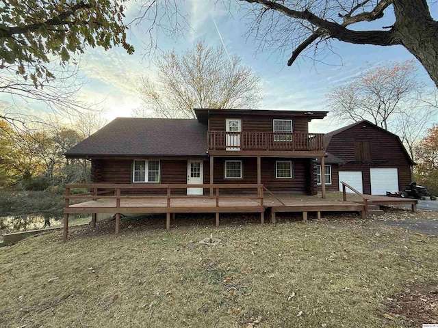 back of property with a wooden deck, a garage, and a lawn